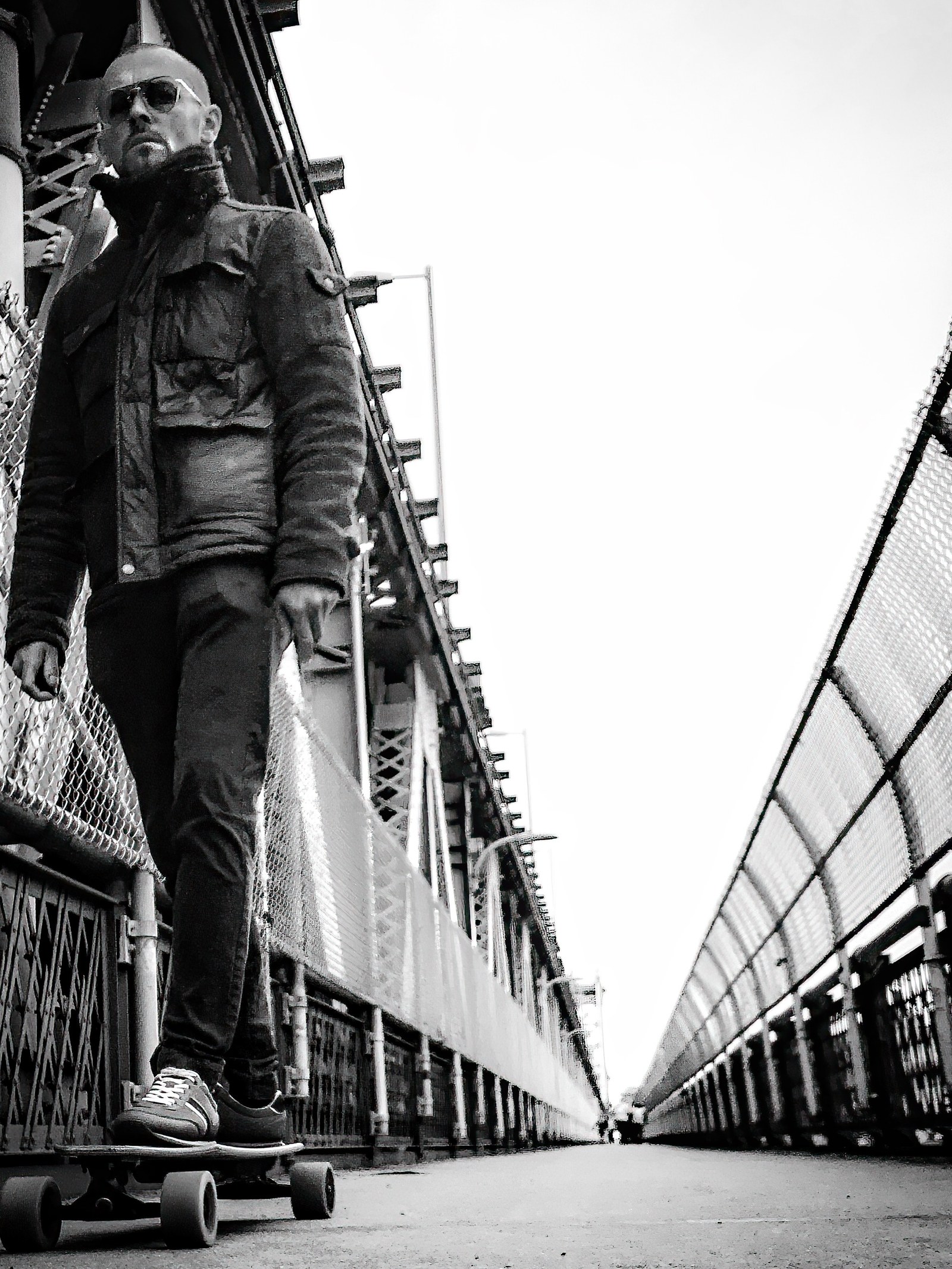 A man riding a longboard across a New York bridge.