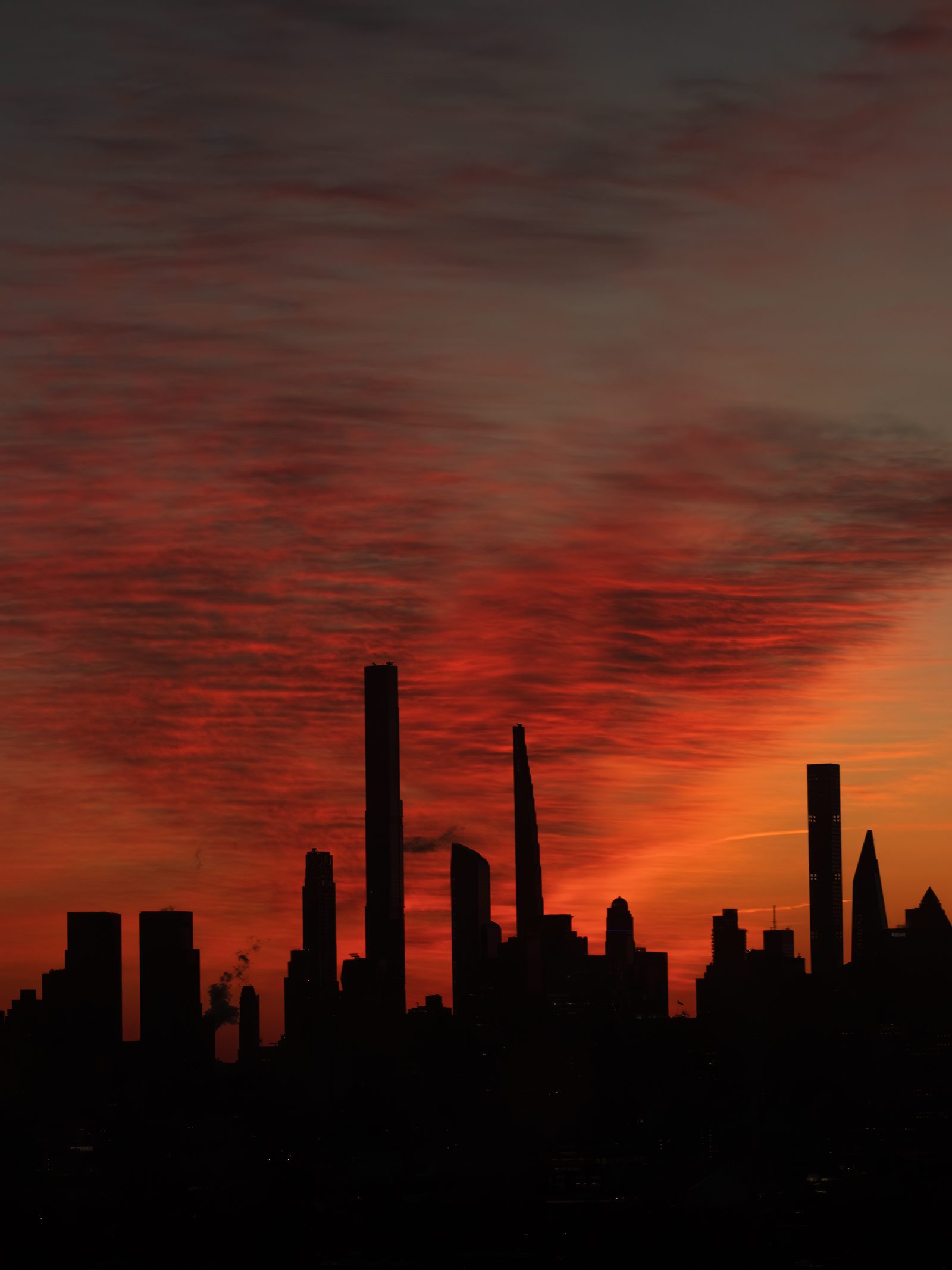 Slender towers in black silhouette against a streaked red and orange sky.